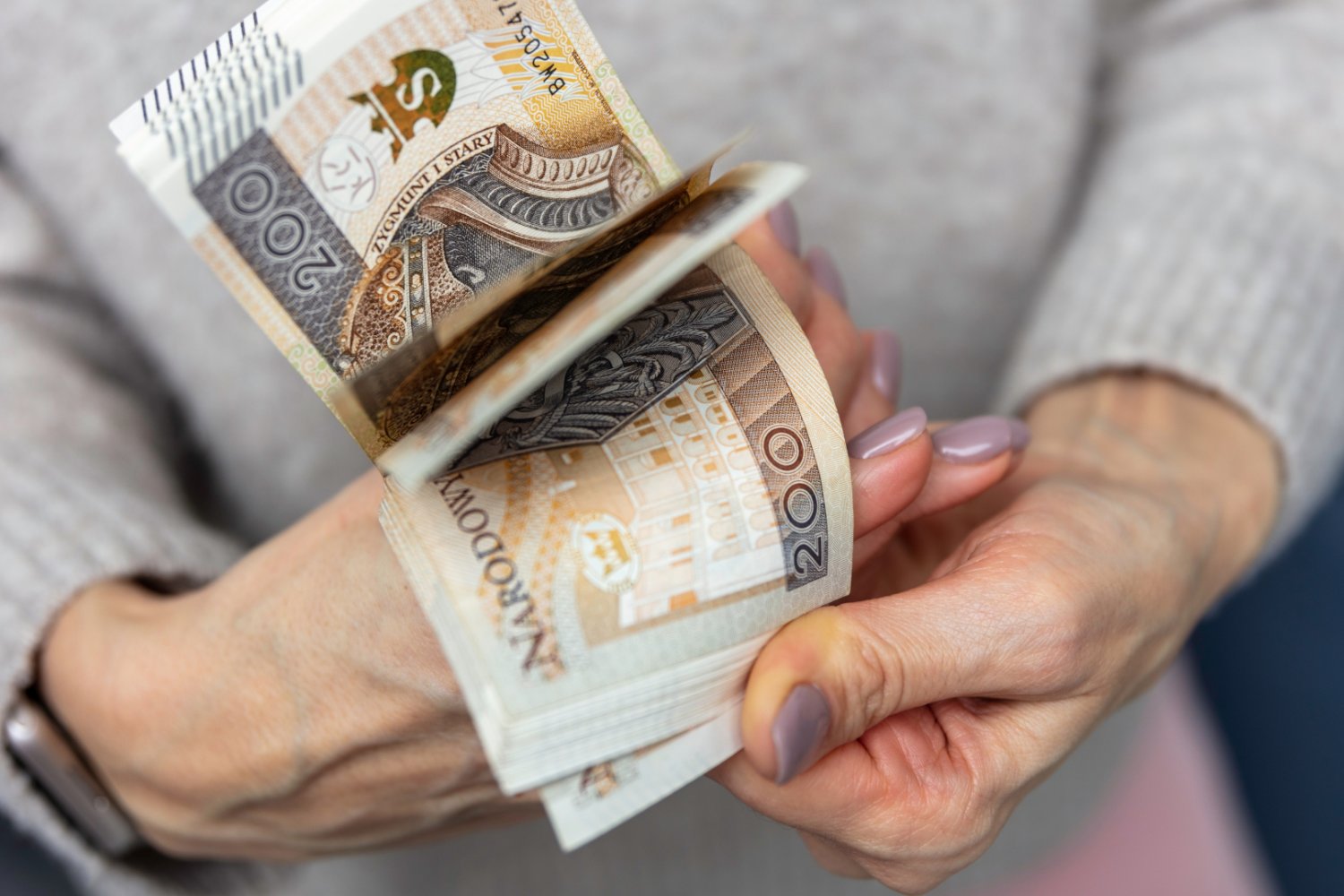 ZUS przeliczy emerytury z urzędu. Jest jeden haczyk, który zamyka drogę do sądu Starsza kobieta licząca polskie banknoty w domu.