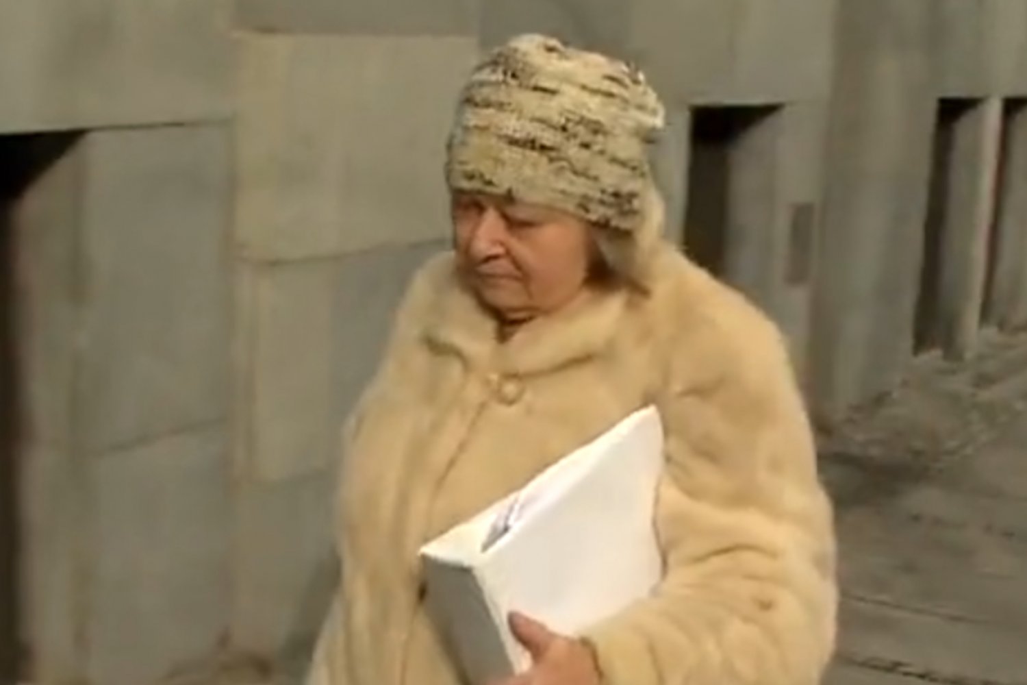 Starsza kobieta w futrze niosąca teczkę
