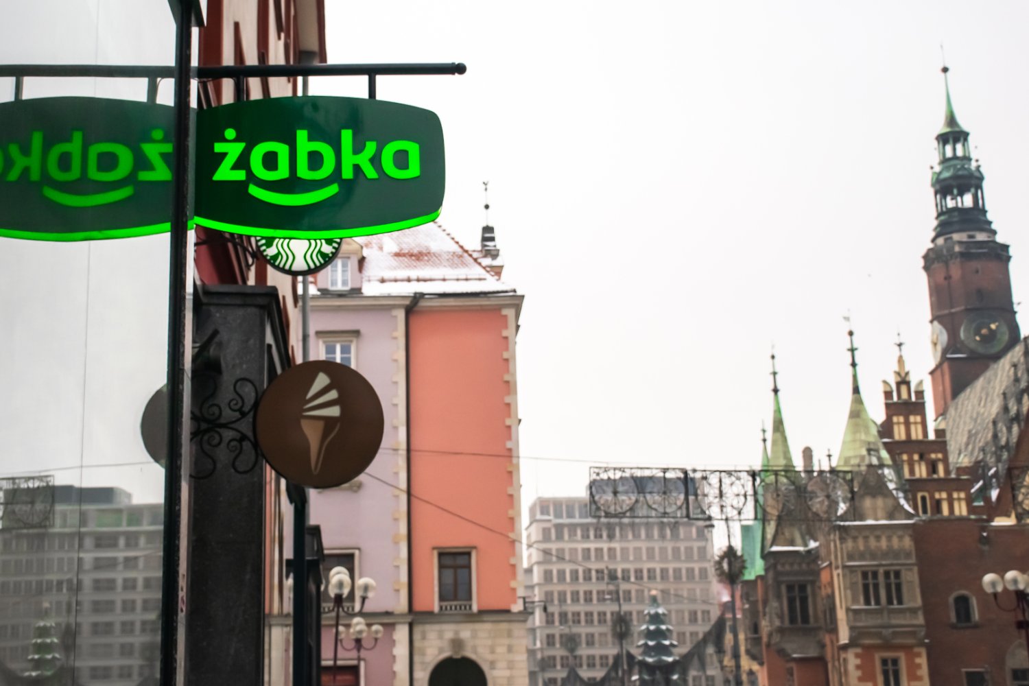 Szyld sklepu Żabka na tle starego miasta w Polsce