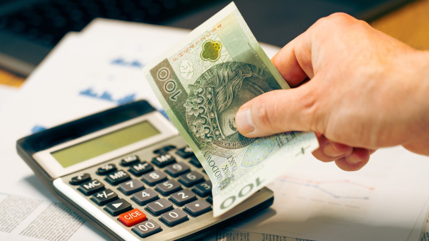 Zbliżenie na dłoń przedsiębiorcy z banknotem 100 zł