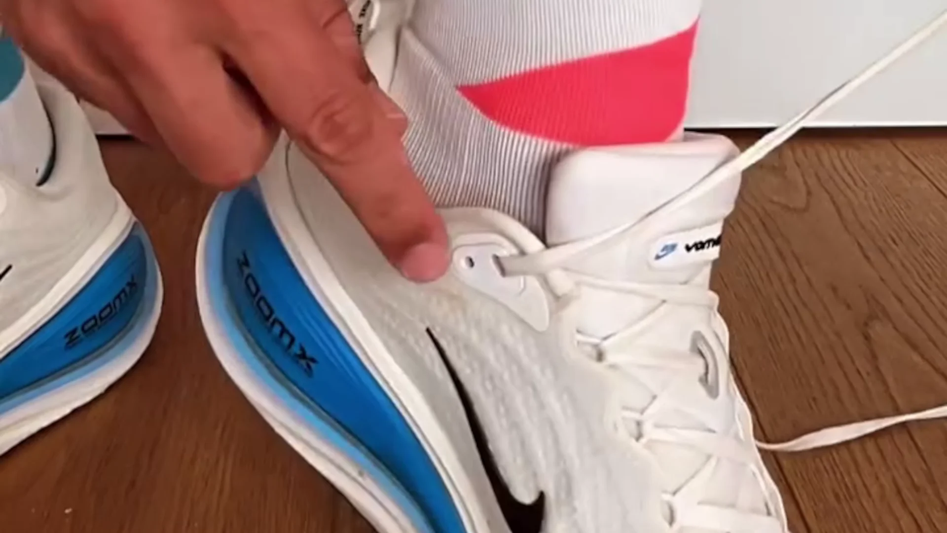 Po co jest dodatkowa dziurka w bucie sportowym? To oczko ma swoją funkcję Zbliżenie na sznurowane buty do biegania. Widoczna dodatkowa dziurka w bucie tuż przy kostce wskazywana palcem