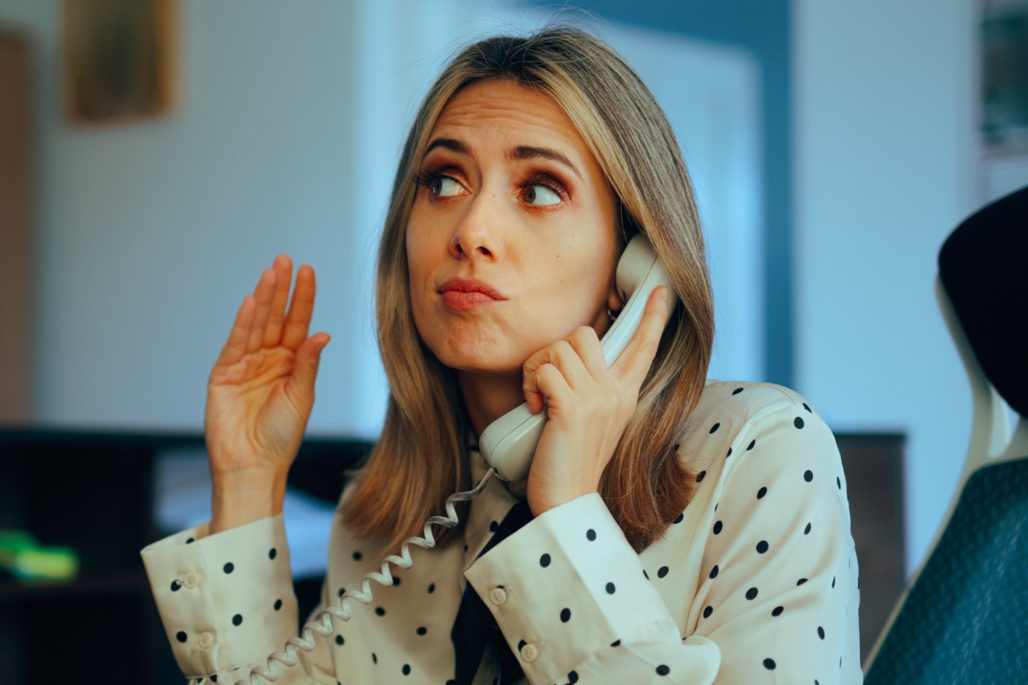 Zirytowana kobieta rozmawia przez telefon i naśladuje dłonią rozmówcę